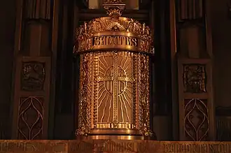 Tabernacle - a fixed, locked box in which the Eucharist is stored