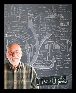 A man says I edit in Wikipedia while standing in front of an educational chalkboard.