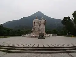 A picture of 2 statues next to each other with a mountain in the background