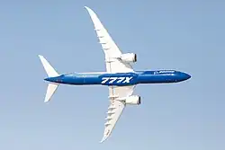 An airliner in flight, photographed from below as it turns, exposing its underside.