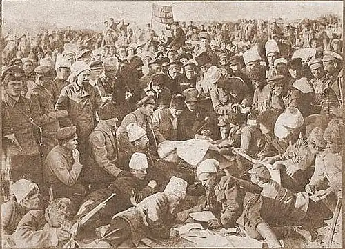 Soldiers gathered around a large sheet of paper, with individuals reading from smaller copies