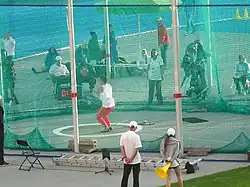 Thrower inside a hammer cage, with the markings for the throwing circle and the throwing sector visible on the ground