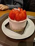 A whole strawberry cake served on a customer table