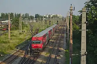 Red train with gray top on the middle track of a three-tracked main line