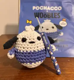 A completed amigurumi crochet dog holding a crochet kit