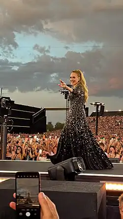 Adele walks on a stage platform in the middle of the crowd