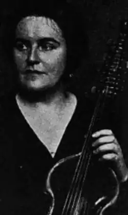 A white woman with dark hair, holding a viola