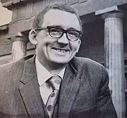 Allen Butterworth, smiling and wearing a suit, is stood outside of the Yorkshire Museum