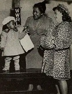 A photograph of a woman standing between two children dressed in fur coats.