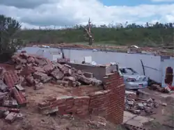 Cinderblocks are strewn around a pile of debris, with the foundation of a home visible.