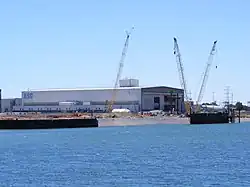 A long, wide building on the shore of a river, with the letters "ASC" on the visible faces.