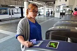 A woman taps her Beep card on one of the turnstiles at an MRT station to exit the platform.