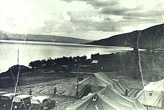 Group of tents and motor cars with Sea of Galilee in background