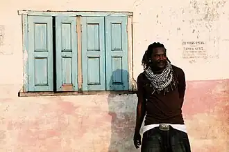 Man standing against a wall with a window to his left