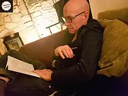 Barry Andrews at home on the sofa with his dog, Wolsey