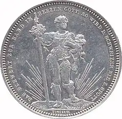 Front–facing male in regalia, holding long sword. Legend along edge.