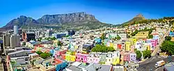 Bo-Kaap area of Cape Town, with its distinctive pastel colored houses in the foreground, the CBD to the left and Table Mountain in the background