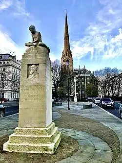 Memorial to Brabazon, unveiled 1934 (artist, Joseph Hermon Cawthra): South face (facing toward Kensington Gardens), bearing bas-relief portrait, in Lancaster Gate, London. Note chemical weathering by acid rain and green stains from algal growth