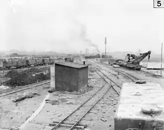 This 1917 photo of the military rail transport at Ypres shows a water tank wagon in the right foreground. Behind the tank wagon is a partially armoured, 16-wheel, hand-operated light railway crane capable of lifting 6 long tons (6.7 short tons; 6.1&nbsp;t). The crane was built by Ransomes & Rapier of Ipswich, Suffolk. Cars in the left background appear to be loaded with crates of food or ammunition.