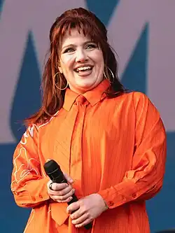 CMAT onstage at Wide Awake 2025, wearing sunglasses, an orange shirt and a tie