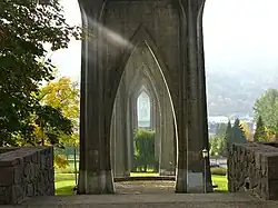 A series of arches on the underside of a bridge; trees and a manicured lawn are visible in the background.