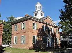 A photograph of a colonial courthouse with brick walls and a white clock spire