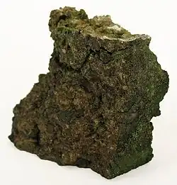 A chunk of chromite showing brown coloring with green oxide.
