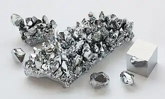 Metallic, reflective crystals of chromium metal and a cube of the same material