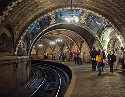 The station as seen from the rear of the platform. The lights are powered on, and there are visitors standing on the platform.