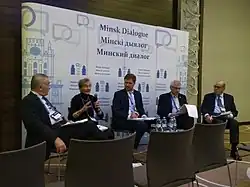 Five people sit in front of a banner at the "Minsk Dialogue" event