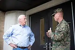 Congressman Greg Pence, left, speaks to a camouflage-wearing military officer, right, outdoors near a doorway