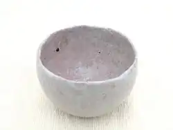 Handmade ceramic tea bowl with rough texture and asymmetry