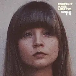 A close-up photo of Courtney Marie Andrews' face against a grey background. Both the artist's name and album title appear on the top right corner of the cover, colored in yellow and white respectively.
