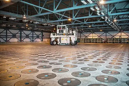 Borosilicate glass is mixed with the waste, heated in a melted until molten, and poured into stainless steel canisters (in the floor here) to harden.