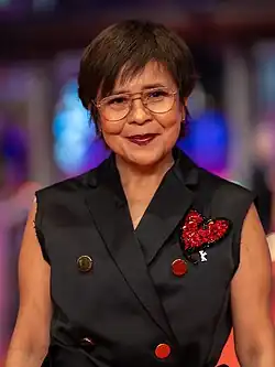 An image of a woman wearing a black sleeveless top and smiling to the camera