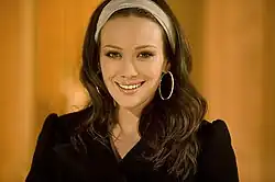 A brunette-haired woman facing a camera and smiling