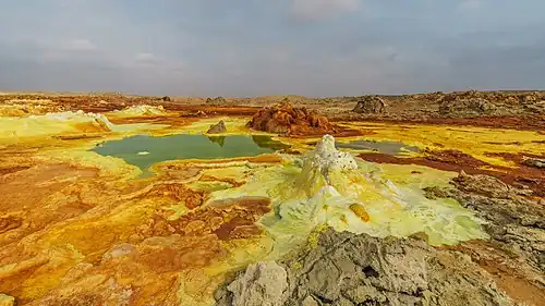 Image 7 Dallol Photograph credit: Alexander Savin Dallol is a cinder-cone volcano in the Danakil Depression, northeast of the Erta Ale Range in Ethiopia. The area lies up to 120 m (390 ft) below sea level, and has been repeatedly flooded in the past when waters from the Red Sea have inundated it. The Danakil Depression is one of the hottest places on Earth, and the evaporation of seawater after these flooding episodes produced thick deposits of salt, as seen in this landscape. The deposits at Dallol include significant quantities of the carbonate, sulfate and chloride salts of sodium, potassium, calcium and magnesium. Hot springs discharge brine to form the blueish ponds, and small, temporary geysers produce cones of salt. More selected pictures