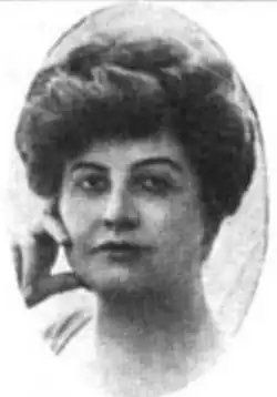 A white woman with dark hair in a bouffant updo, hand on cheek