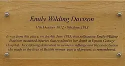 Plaque dedicated to Davison. In addition to her name and dates, the text reads "It was from this place, on the 4th June 1913, that suffragette Emily Wilding Davison sustained injuries that resulted in her death at Epsom Cottage Hospital. Her lifelong dedication to women's suffrage and the contribution she made to the lives of British women past and present, is remembered.