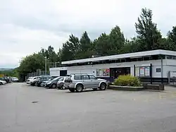 A low flat-roofed building with cars parked outside