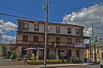 The front of an inn, three stories high, with a balcony on the second floor.