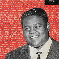 A black and white photo of Domino smiling with the album name repeated behind him