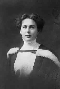 A young woman with dark hair in fur-rimmed graduation robes