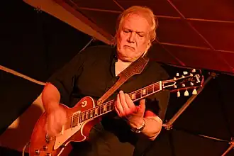Luboš Andršt performing onstage, looking intently at his guitar