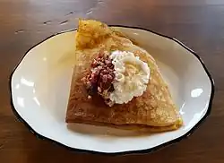 A sweet crêpe filled with oats and berries and topped with whipped cream
