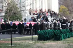 A funeral procession with two coffins wrapped in the United States flag