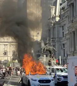 A police car on fire with "ACAB" spray painted onto it