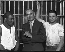 George R. Dale wearing a suit in front of prison bars, surrounded by two men