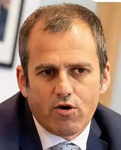 portrait of a 40ish-year-old male with a close-cropped hair wearing a dark blue suit