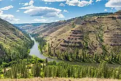View over a river bend framed by high cliffs of horizontally layered rock